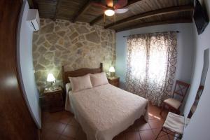 sypialnia z łóżkiem i kamienną ścianą w obiekcie Casas Rurales El Caminante w mieście Aldeanueva del Camino