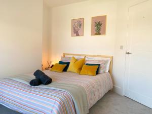 a bedroom with a bed with yellow and blue pillows at Stunning New House - Great Location - Garden - Parking - Fast WiFi - Smart TV - Beautiful 2 Bedroom House sleeps up to 6! Only 5 min drive to Sandbanks beach! in Parkstone
