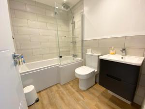 a bathroom with a toilet and a sink and a bath tub at Stunning New House - Great Location - Garden - Parking - Fast WiFi - Smart TV - Beautiful 2 Bedroom House sleeps up to 6! Only 5 min drive to Sandbanks beach! in Parkstone