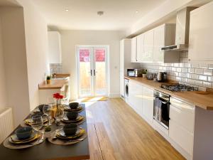 a kitchen with a table with plates on it at Stunning New House - Great Location - Garden - Parking - Fast WiFi - Smart TV - Beautiful 2 Bedroom House sleeps up to 6! Only 5 min drive to Sandbanks beach! in Parkstone