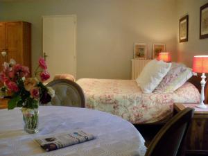 a room with a bed and a table with a vase of flowers at La Metairie du Pont in Sainte-Hermine