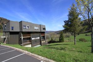 ein Haus mit einem Parkplatz davor in der Unterkunft Studio Village des Longes in Le Mont-Dore