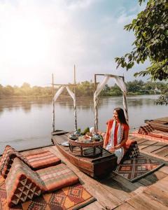 una mujer sentada en un barco en el agua en The Antique Riverside Resort, en Ban Pong