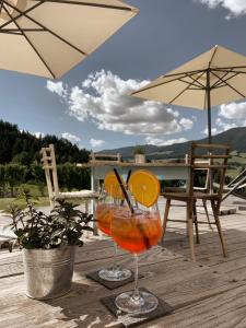 two glasses of orange juice sitting on a wooden deck at Gailerhof Hotel B&B Superior in Monguelfo