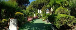 un giardino alberato e un prato verde con tavoli e sedie di Residence Carducci a Cesenatico