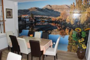 ein Esszimmer mit einem Tisch, Stühlen und einem Wandbild in der Unterkunft Hotel San in Trebinje