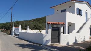 a white house with a door on the side of a street at Marko's Cozy Apartment in Megalochori
