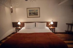 a bedroom with a large bed with two lamps at Hotel Solar Das Lajes in Ouro Preto