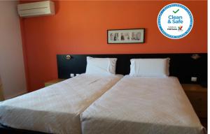Hotel Riomar في لاغوس: سرير كبير في غرفة النوم بجدار برتقالي