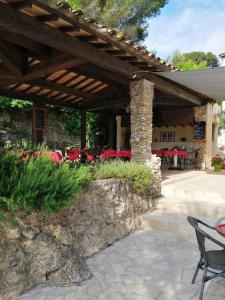 a patio with a wooden pergola with tables and chairs at Auberge La Folie in Sausset-les-Pins
