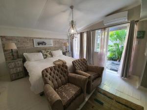 um quarto com uma cama, um sofá e uma cadeira em Waterhouse Guest Lodge in Muckleneuk em Pretoria