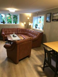 a living room with a brown leather couch and a table at Josygaard in Austefjorden
