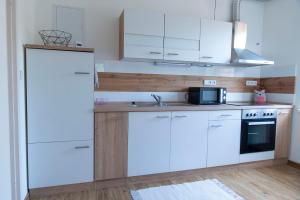 a kitchen with white cabinets and a microwave at Apartmán u Větrníku in Jihlava