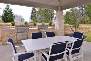 Candlewood Suites - Austin Airport, an IHG Hotel في أوستن: طاولة بيضاء وكراسي على فناء مع شواية