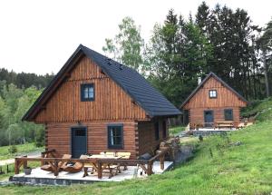 domek z bali ze stołami piknikowymi przed nim w obiekcie Roubenky Bublava w mieście Bublava