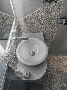 a white sink in a bathroom with a stone wall at Haraki Village in Haraki