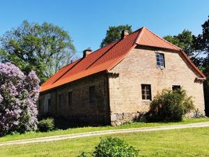 an old brick building with an orange roof at Pilkalnes muiža in Nereta