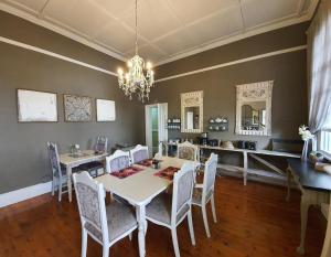 uma sala de jantar com uma mesa e cadeiras e um lustre em Waterhouse Guest Lodge in Muckleneuk em Pretoria