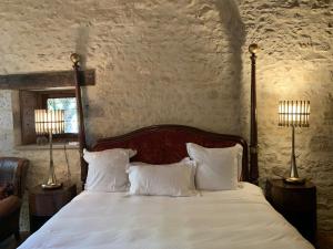 una camera da letto con un letto con lenzuola bianche e due lampade di Demeure des Vieux Bains a Provins