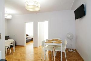a white dining room with a table and chairs at P&J Apartments Floriańska in Krakow