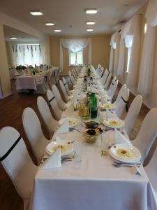 a long table in a room with white tables and chairs at Willa Wiktoria in Międzylesie