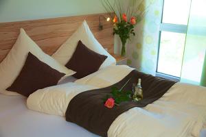 Una cama con un montón de almohadas con una botella. en Lohauserhof - Biohof und Hotel, en Röhrmoos