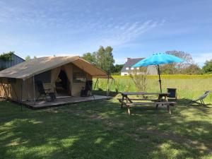 ein Zelt, ein Picknicktisch und ein Sonnenschirm in der Unterkunft Tente Lodge les Gîtes de l'Odet in Lanio