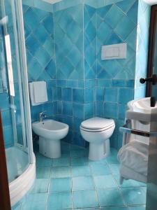 Baño de azulejos azules con aseo y lavamanos en Hotel Corallo Sperlonga, en Sperlonga