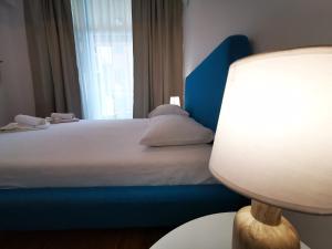 sypialnia z łóżkiem z niebieskim zagłówkiem i lampką w obiekcie Apartamente Gala Residence Eforie Nord w mieście Eforie Nord