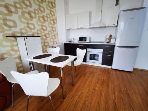 Apartamente Gala Residence Eforie Nord في إيفوري نورد: مطبخ به أجهزة بيضاء وطاولة وكراسي