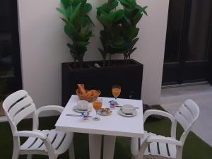 een witte tafel met twee stoelen en twee glazen sinaasappelsap bij Hôtel Emilie in Royan