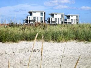 two houses on top of a beach with tall grass at 4 person holiday home in Wendtorf in Wendtorf