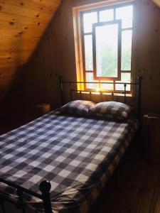 łóżko w pokoju z oknem w obiekcie LeśneEcho - domek w drzewach w mieście Żdżar