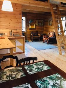 a living room with a kitchen and a staircase in a cabin at LeśneEcho - domek w drzewach in Żdżar