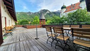 a wooden deck with chairs and tables and mountains at Wirtshaus zum Baumbach in Aschau im Chiemgau