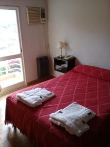 1 dormitorio con 1 cama roja y 2 toallas en Apart Hotel Marilian en Salta