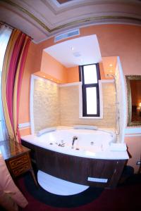 La salle de bains est pourvue d'une grande baignoire et d'une fenêtre. dans l'établissement Vigo Hotel, à Ploieşti