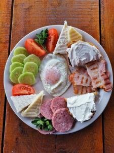 a plate of breakfast food with eggs sausage waffles and tomatoes at Casa Suzy & Roxy in Arpaşu de Jos