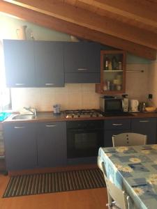 cocina con armarios azules, fogones y mesa en Villa Gemelli, en Castellanza