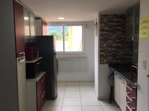 a kitchen with a black refrigerator and a window at Vista Lateral Mar Massaguaçu in Caraguatatuba +46 photos