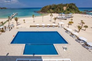 eine Luftansicht auf einen Strand mit einem Pool in der Unterkunft Kariyushi LCH. Resort in Nago