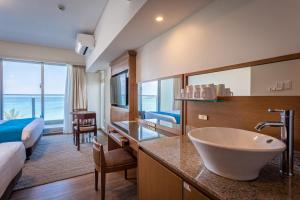 a hotel room with a bathroom with a sink and a bed at Kariyushi LCH. Resort in Nago