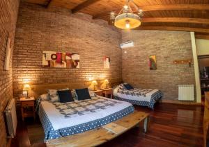 una camera con due letti e un muro di mattoni di Lujan De Cuyo B&B a Ciudad Lujan de Cuyo