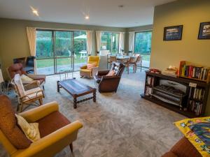 a living room with couches and chairs and a fireplace at Tasman Treat - Marahau Holiday Home in Marahau