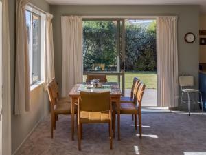 uma sala de jantar com uma mesa e cadeiras e uma janela em Tasman Treat - Marahau Holiday Home em Marahau