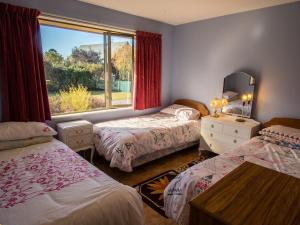 1 dormitorio con 2 camas y ventana en Tasman Treat - Marahau Holiday Home, en Marahau
