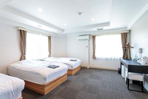 Habitación de hotel con 2 camas y escritorio en Stay Inn Will en Saitama