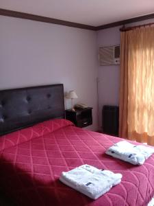 1 dormitorio con 1 cama rosa y 2 toallas en Apart Hotel Marilian en Salta