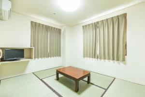 un soggiorno con un tavolo e una TV di Tabist Business Hotel Kaigansou Gamagori a Gamagōri