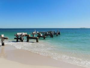 a group of wooden tables in the water on a beach at Cottage 57 - Topspot Cottages in Jurien Bay